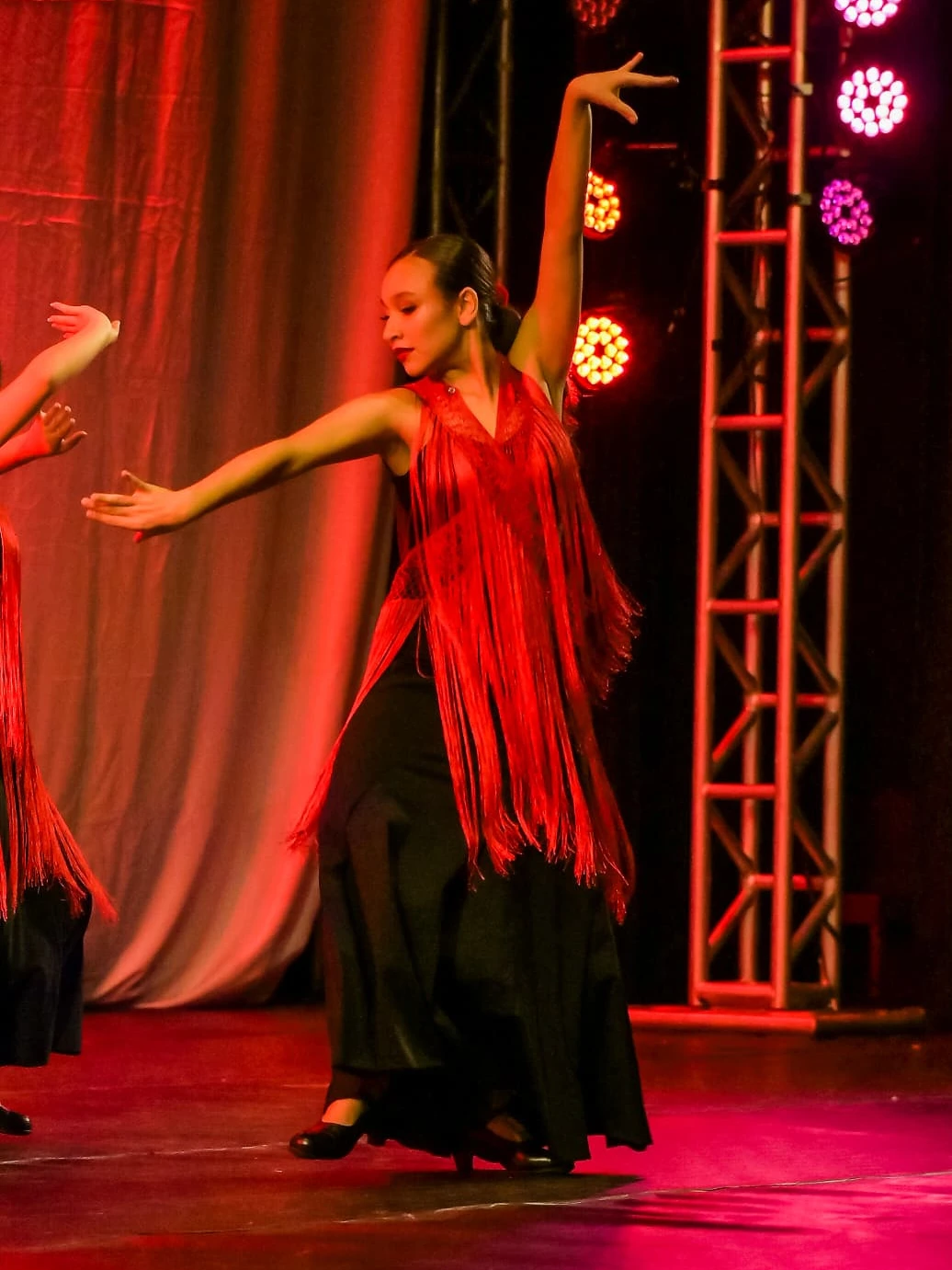 Bailarina de danza española con vestido de flecos rojo en escena